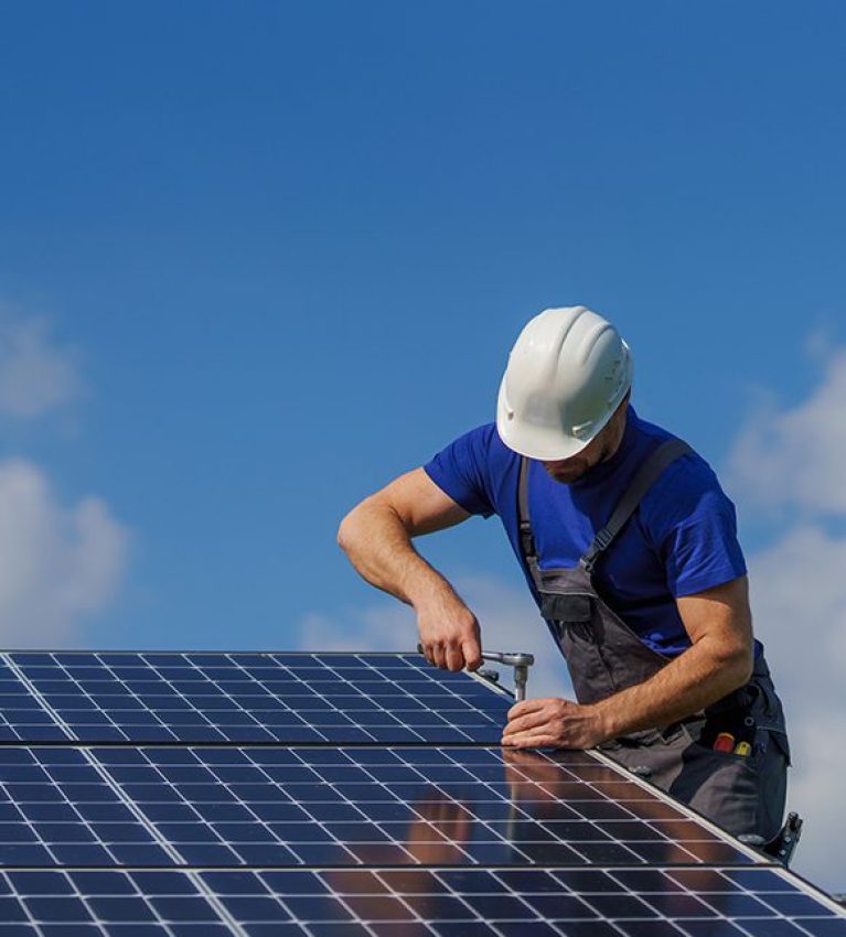 Man worker installing solar photovoltaic panels on roof, alternative energy concept.