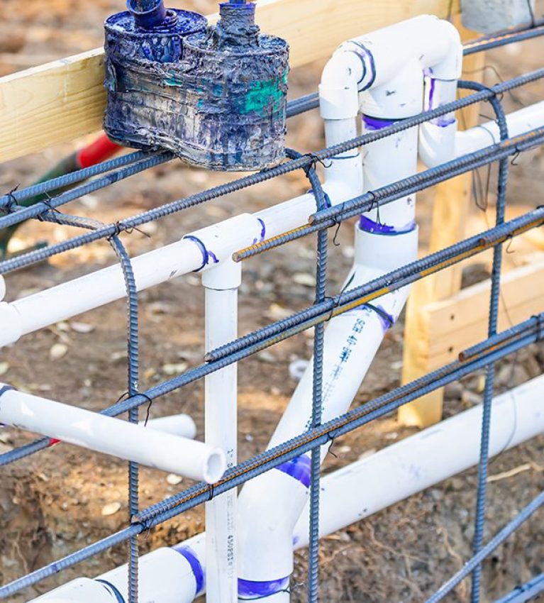 Newly Installed PVC Plumbing Pipes and Steel Rebar Configuration At Construction Site.