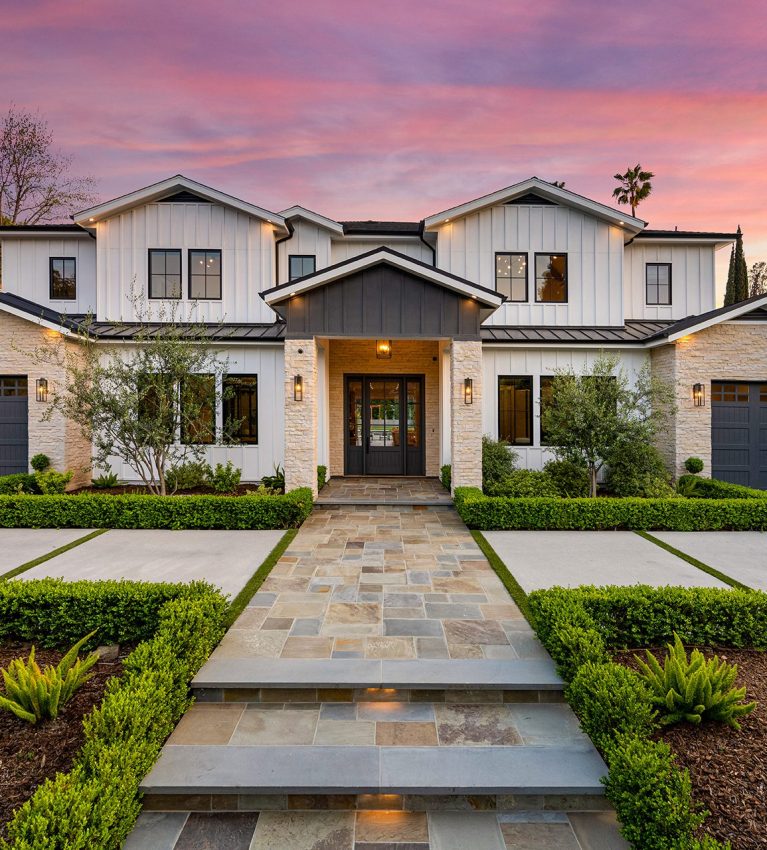 the house is surrounded by hedges and trees with palm trees around it