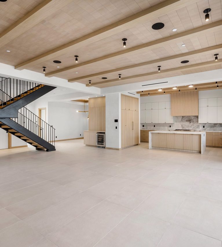 the interior of a house with an empty space and a staircase leading to the kitchen